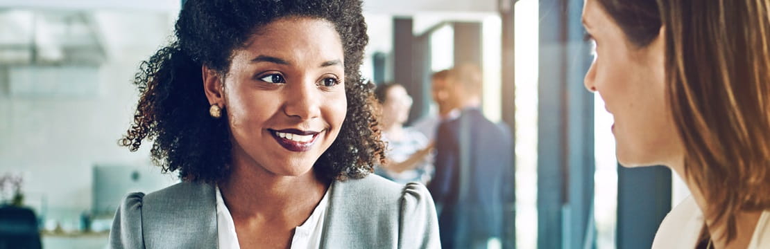 Two businesswomen speaking in an office.